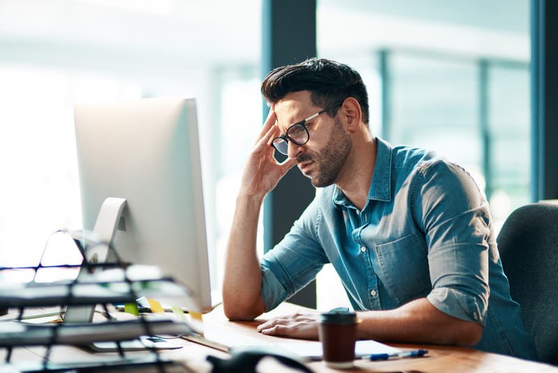 Homme travaillant devant en ordinateur et souffrant de TMS